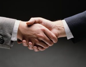 Two businessmen in suits shaking hands, a positive gesture